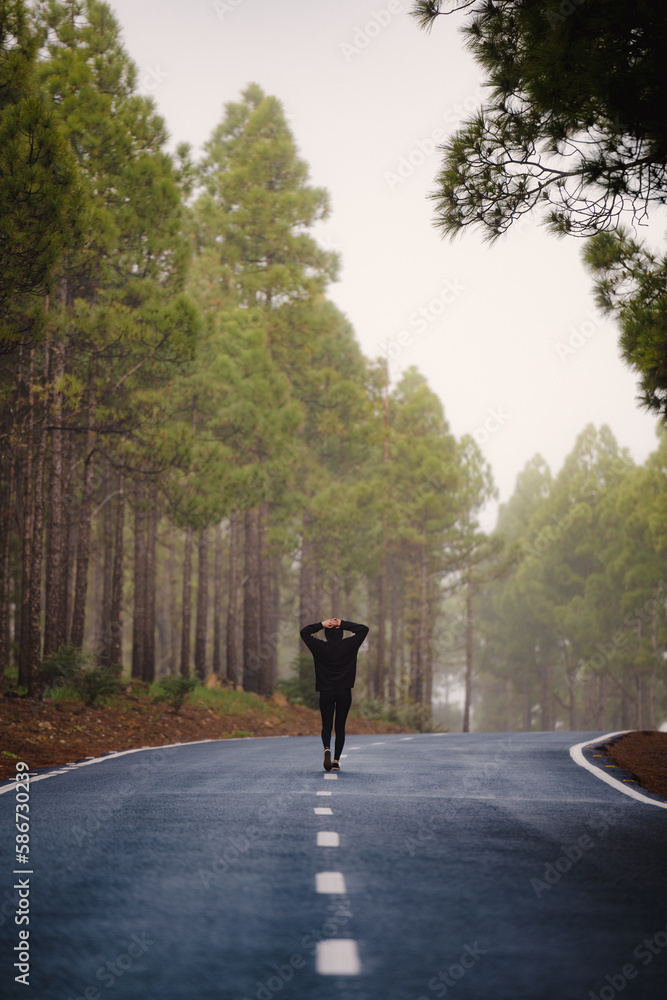 Stunning view of a girl walking on a road that crosses a beautiful forest. Pico de las Nieves, Gran Canaria, Canary Islands.
