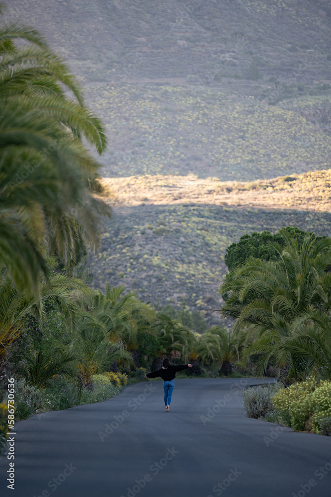 Stunning view of a girl walking on a road that crosses a beautiful forest. Pico de las Nieves, Gran Canaria, Canary Islands.