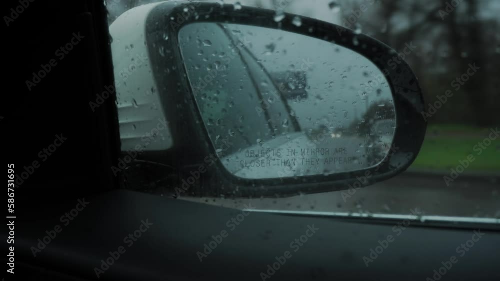 Close-up. Blind Spot Monitor Lights up on the side mirror of the car when overtaking, while driving on the road in the rain Close-up. Blind Spot Monitor Lights up on the side mirror of the car when overtaking, while driving on the road in the rain