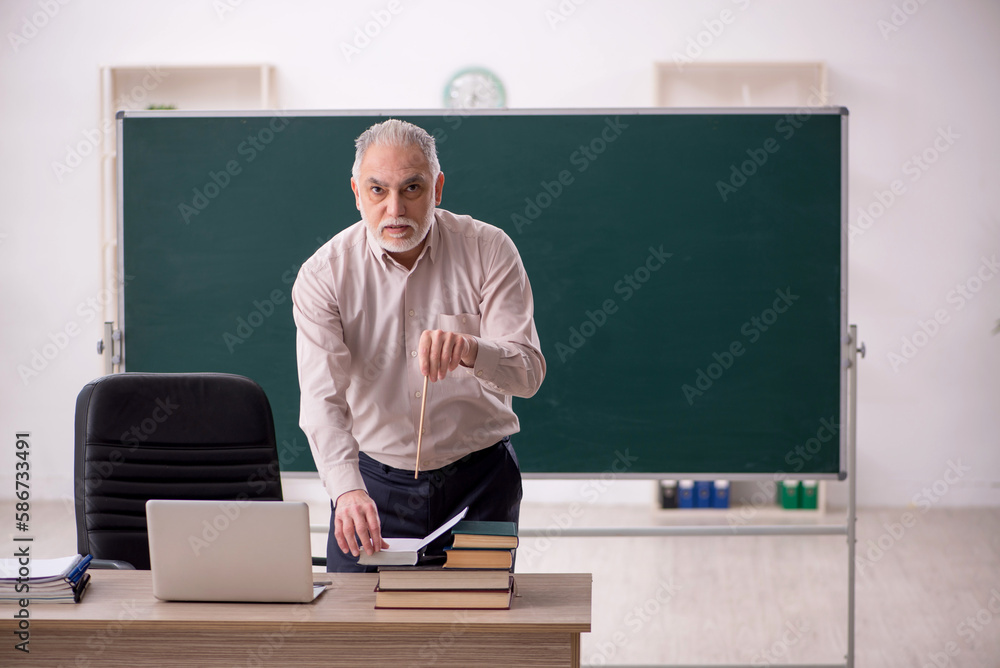 Old male teacher in the classroom Old male teacher in the classroom