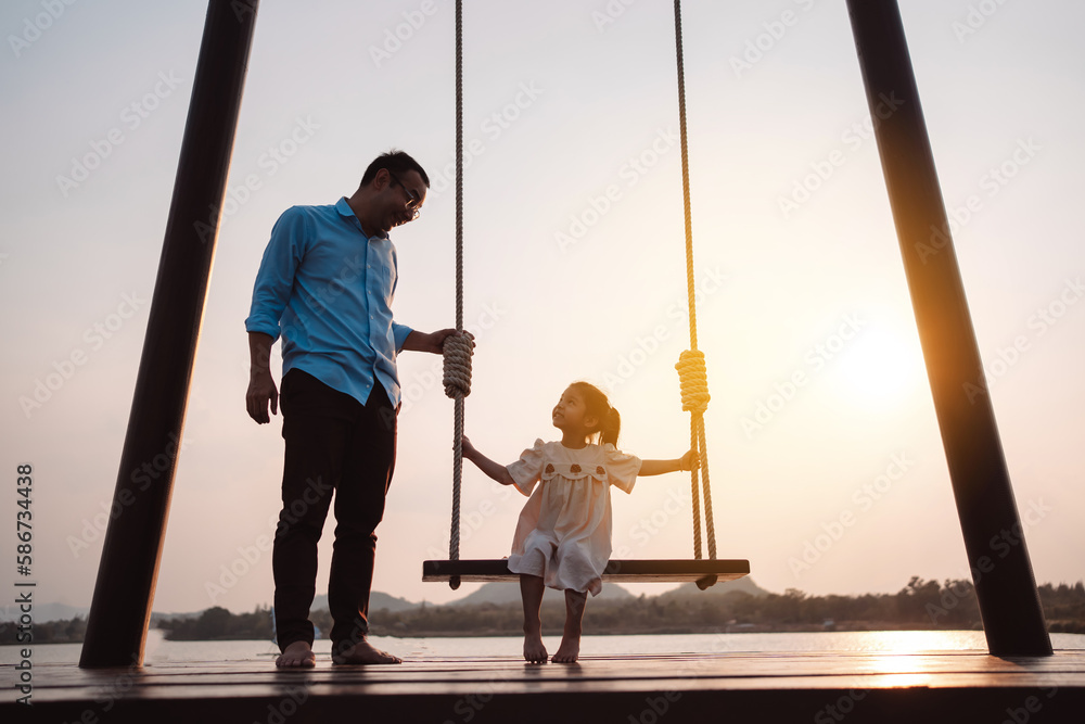Happy family enjoying with swing in the park at sunset outdoor in nature, Weekend activity of family life together. Happy family enjoying with swing in the park at sunset outdoor in nature, Weekend activity of family life together.