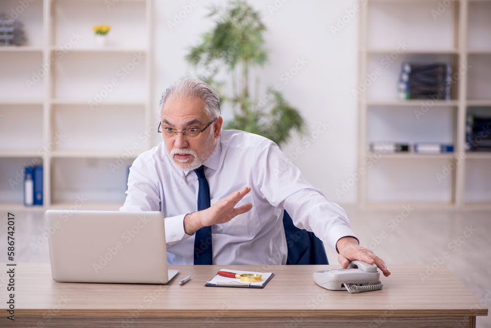 Old male boss working at workplace Old male boss working at workplace