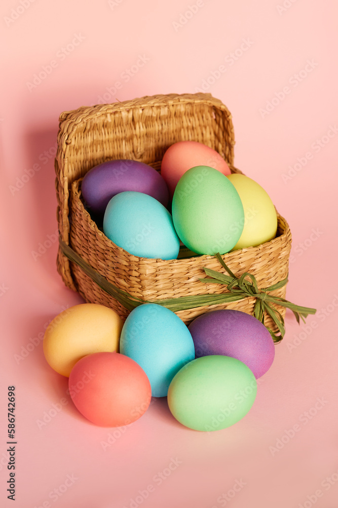 Colored Easter eggs in a square basket on a pink background. Easter Colored Easter eggs in a square basket on a pink background. Easter