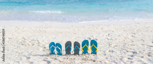 Three pairs of flip flops on the beach on the background of ocean in the Maldives. Family vacation. Banner