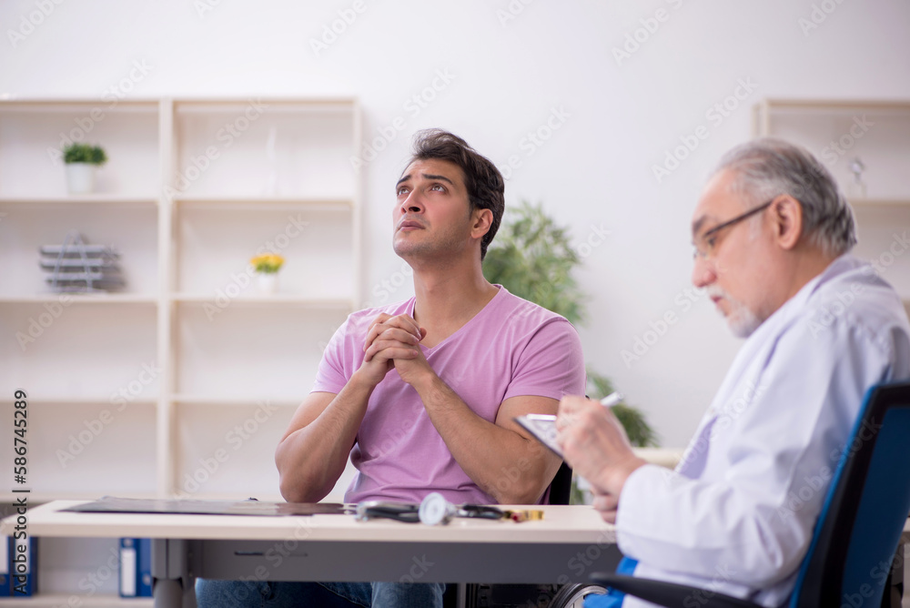 Young patient in wheelchair visiting old doctor Young patient in wheelchair visiting old doctor