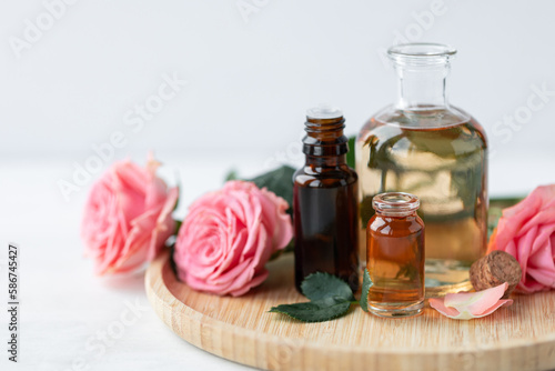 Aromatherapy. Concept of pure organic essential rose oil. Elixir with plant based floral or herbal ingredients. Pink flowers extract. Spa atmosphere with candle  towel. White background