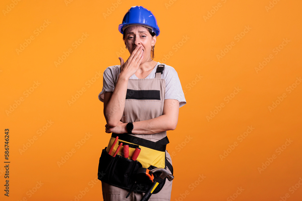 Sleepy overworked builder yawning and feeling tired, falling asleep wearing overalls in studio. Exhausted construction worker being fatigued and feeling burnout after building work. Sleepy overworked builder yawning and feeling tired, falling asleep wearing overalls in studio. Exhausted construction worker being fatigued and feeling burnout after building work.