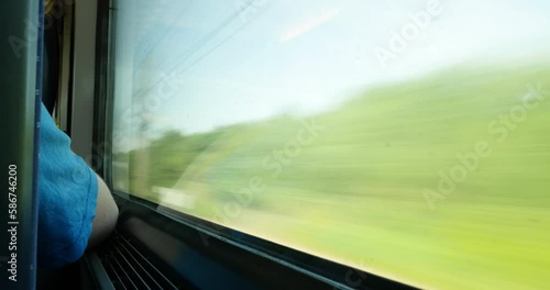 A blurred shot of a train window, showing the speed and green landscape passing by as it travels along its railroad tracks. photo