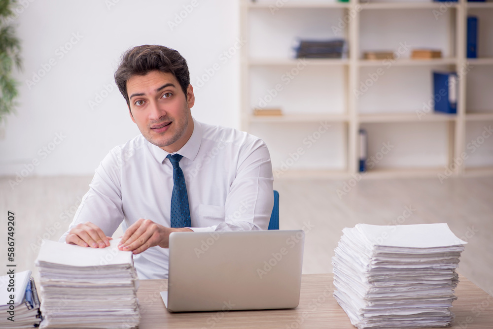 Young male employee and too much work in the office Young male employee and too much work in the office