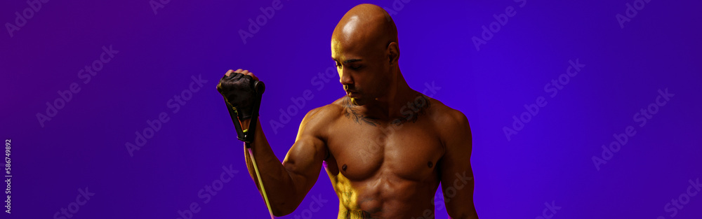 Fototapeta premium Sporty man performs exercises with expander on studio background. Strength and motivation