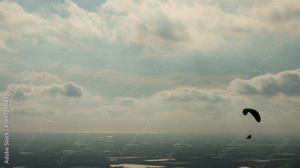 Two paragliders move peacefully and slowly in the cloudy sky. The sport of paragliding gives a feeling of tranquility, peace, strength and freedom in the open air Two paragliders move peacefully and slowly in the cloudy sky. The sport of paragliding gives a feeling of tranquility, peace, strength and freedom in the open air