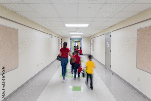 School kids with teachers walking out of a school in a row