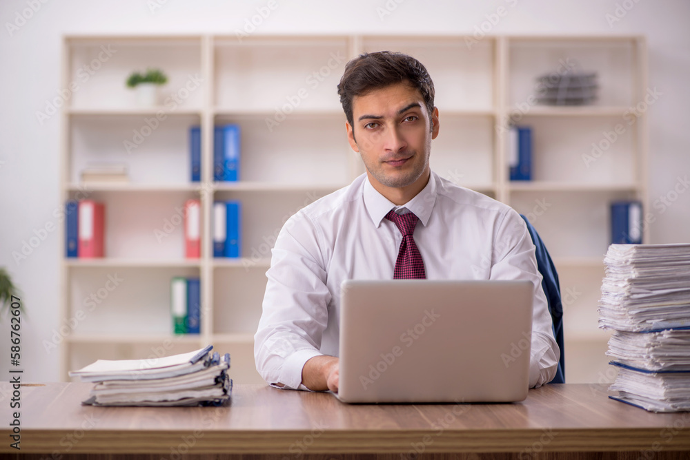 Young male employee and too much work in the office Young male employee and too much work in the office