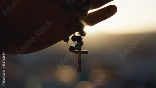 Hands clasp rosary at sunset photo