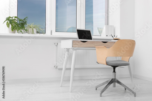 Comfortable workplace near window in stylish room. Home office