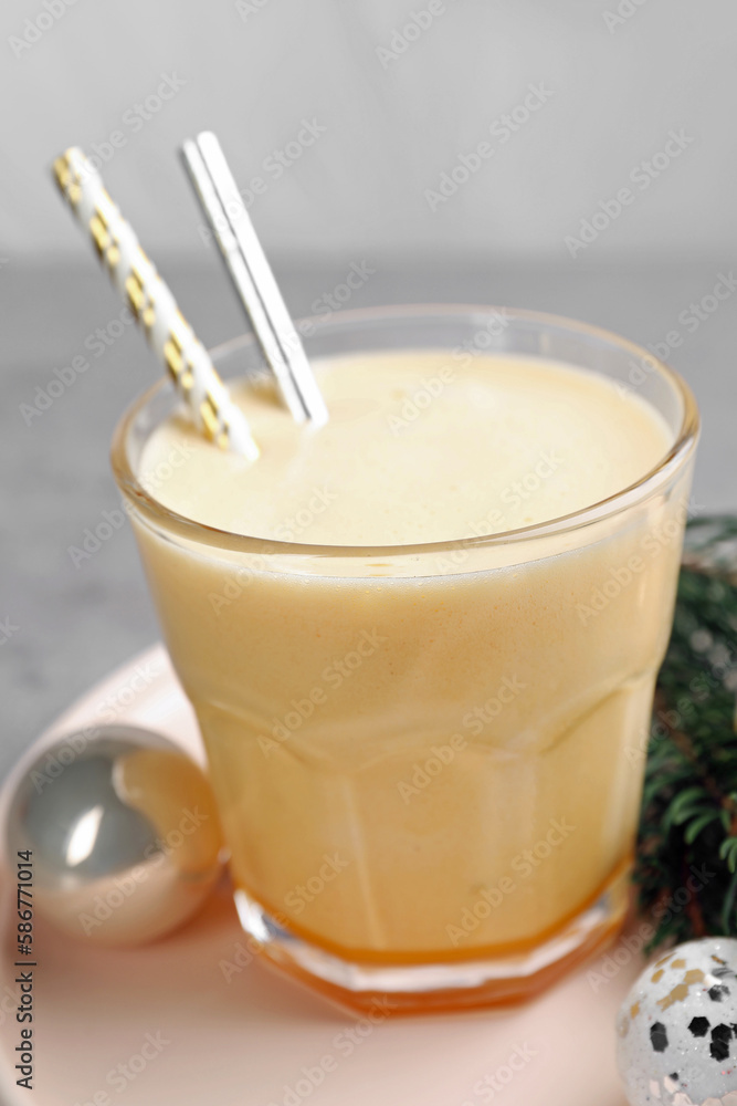 Glass of delicious eggnog and decorated fir branch on gray table, closeup Glass of delicious eggnog and decorated fir branch on gray table, closeup