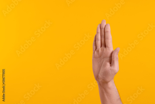 Man giving high five on yellow background, closeup of hand. Space for text