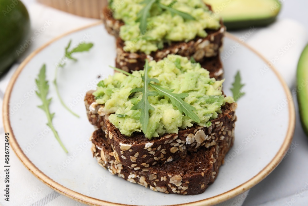 Delicious sandwiches with guacamole and arugula on plate, closeup Delicious sandwiches with guacamole and arugula on plate, closeup