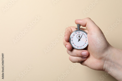 Man holding vintage timer on beige background, closeup. Space for text