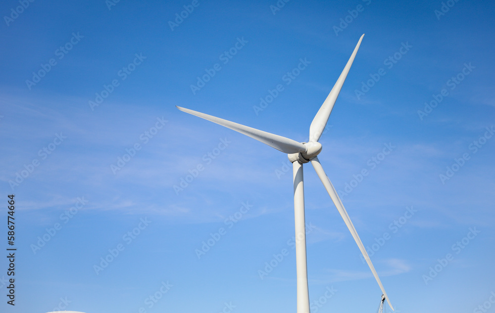 wind turbine standing tall against a clear blue sky, symbolizing sustainability, renewable energy, and the use of alternative energy resources in industry