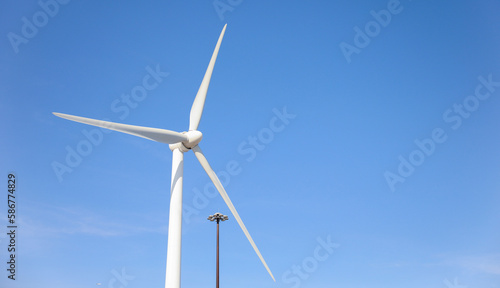 wind turbine standing tall against a clear blue sky, symbolizing sustainability, renewable energy, and the use of alternative energy resources in industry