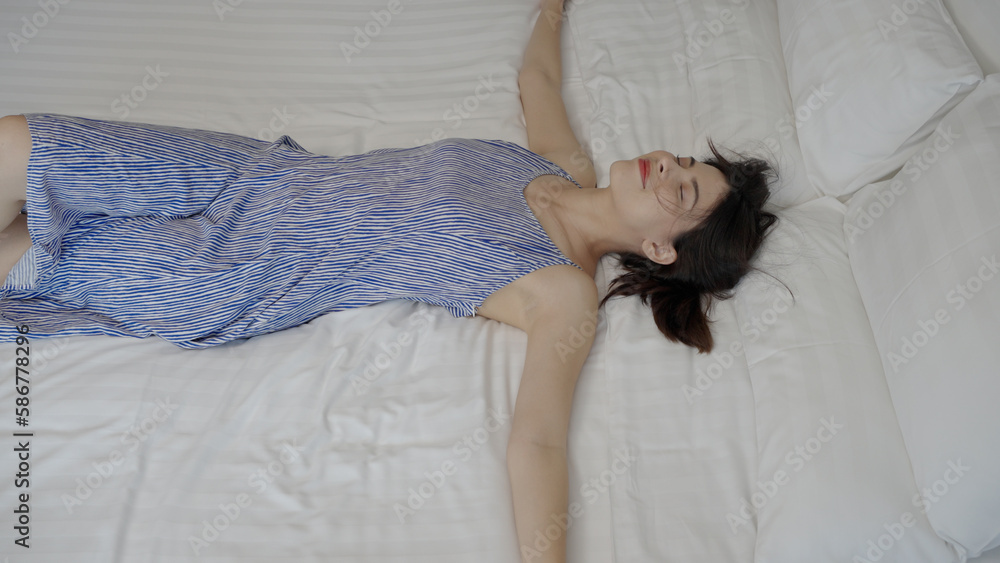 Beautiful woman in a blue dress fell happily on the bed in a hotel room. Summer vacation lifestyle. Beautiful woman in a blue dress fell happily on the bed in a hotel room. Summer vacation lifestyle.