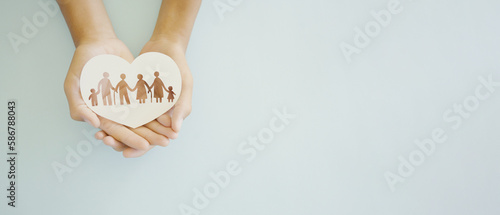 Hands holding multi generational family in heart shape paper, family wellness, health insurance concept