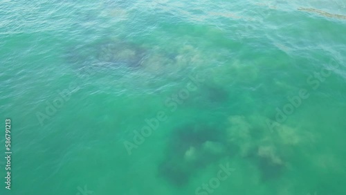 Drone looking down at turquoise Indian Ocean waters, rotating and rising up in slow motion. photo