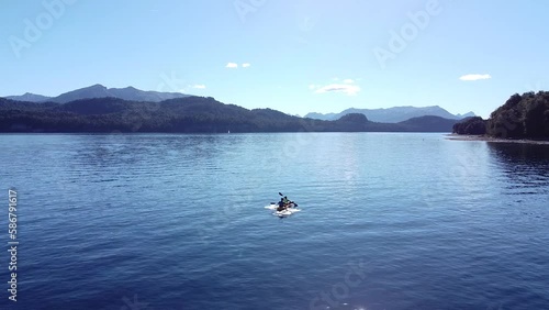 Aerial static shot of a Kayak with two people in the lake of Nahuel Huapi in Patagonia Argentina with Andes mountain range in the background. photo