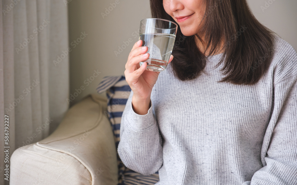 Closeup image of a young woman holding and drinking water
