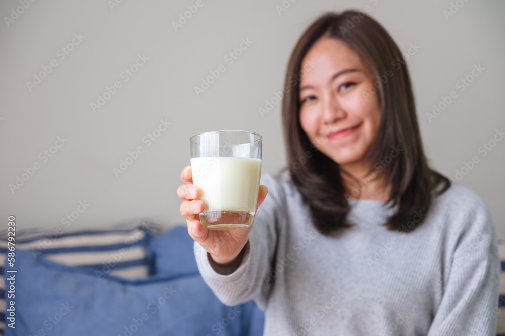 Portrait image of a young woman holding and showing a glass of fresh milk Portrait image of a young woman holding and showing a glass of fresh milk