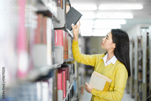 Student choosing and reading book at library.