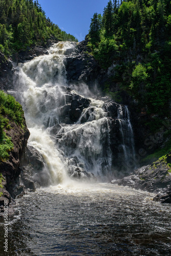 Ouiatchouan Waterfall in the forest of Quebec, Canada, among trees