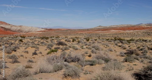 Drive Plate-View from passenger side window passing low desert vegetation with red hills in the background in the dry Arid Mojave Desert of Southern Nevada