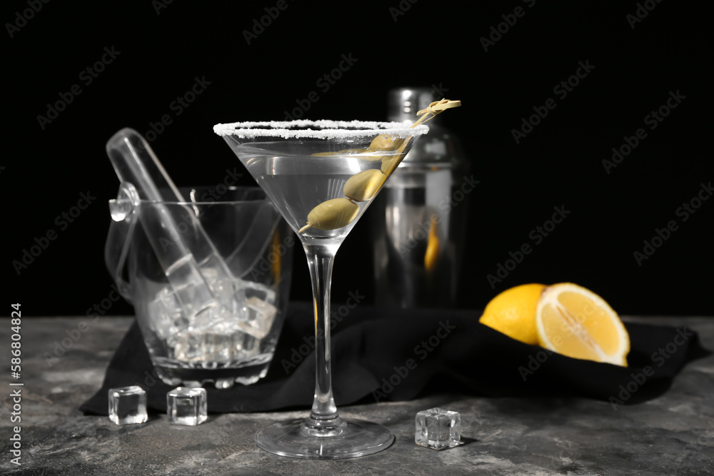 Glass of tasty martini with olives, ice cubes and lemon on dark background Glass of tasty martini with olives, ice cubes and lemon on dark background