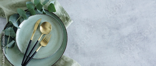 Modern minimal table place setting neutral green color on gray concrete background top view.Banner.  Space for text .  Modern kitchen.Scandinavian style.