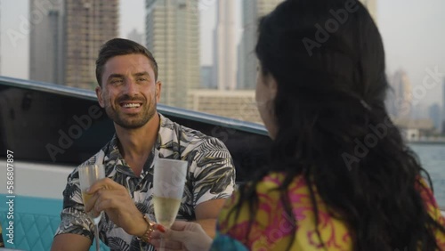 Slow motion shot of a man and attractive female drinking champaign during sunset on a yacht in Dubai photo