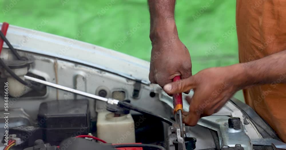 A man is fixing a car with pliers, or flat-nosed pliers, or wire cutters. A man is fixing a car with pliers, or flat-nosed pliers, or wire cutters.