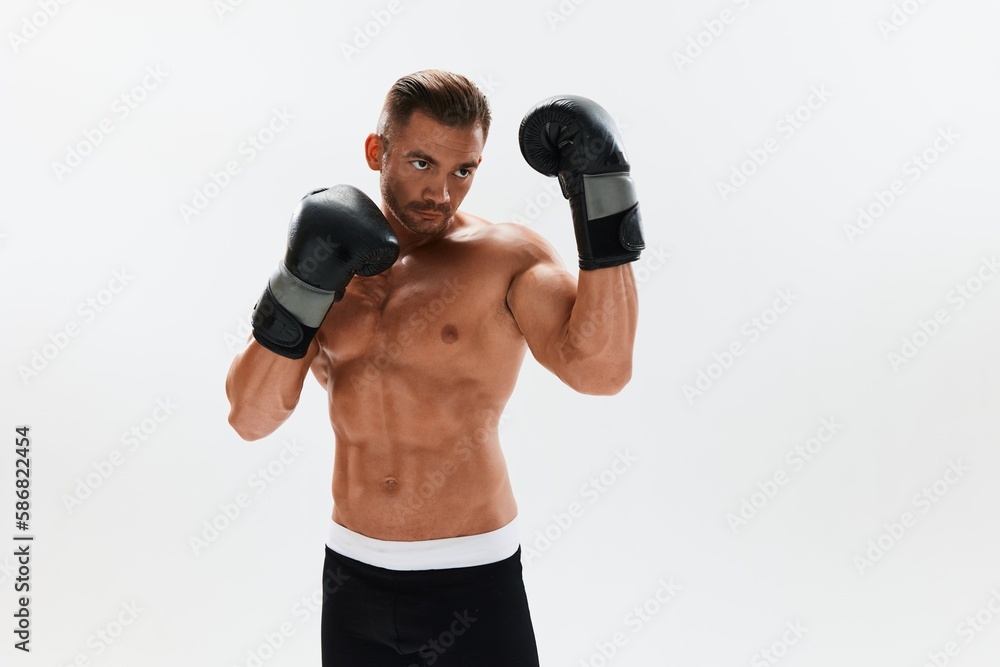 Man athletic bodybuilder poses in boxing gloves with nude torso abs in full-length background, boxing and martial arts. Advertising, sports, active lifestyle, competition, challenge concept. 