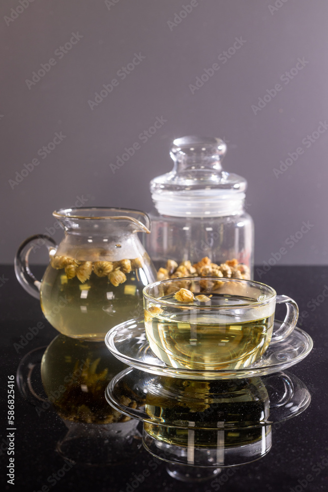 Organic Chrysanthemum flower tea in a cup and teapot on black background, Healthy Herbal drink Organic Chrysanthemum flower tea in a cup and teapot on black background, Healthy Herbal drink