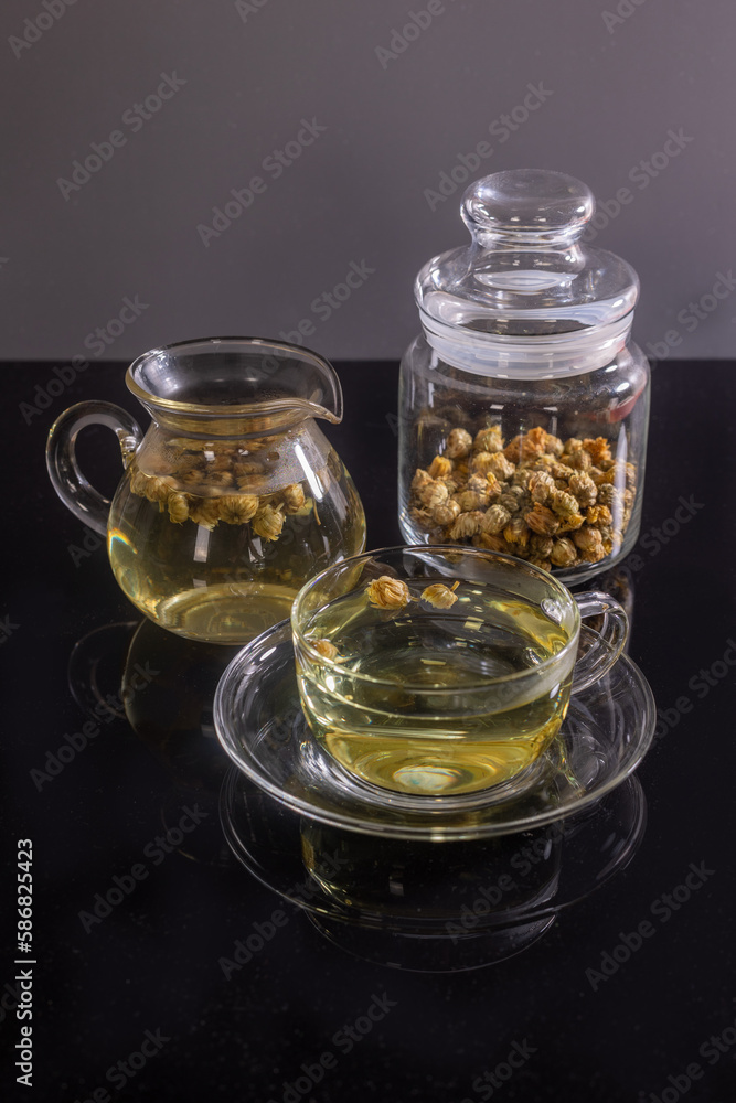 Organic Chrysanthemum flower tea in a cup and teapot on black background, Healthy Herbal drink Organic Chrysanthemum flower tea in a cup and teapot on black background, Healthy Herbal drink