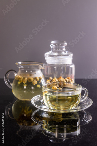 Organic Chrysanthemum flower tea in a cup and teapot on black background, Healthy Herbal drink