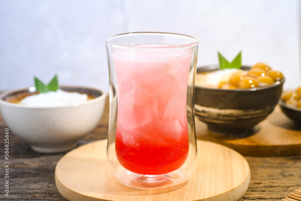 a glass of coconut water with red syrup on a wooden table. Coconut water can prevent vomiting and treat dehydration. Ramadan iftar meal a glass of coconut water with red syrup on a wooden table. Coconut water can prevent vomiting and treat dehydration. Ramadan iftar meal