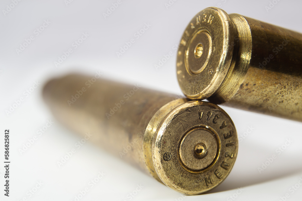 two machine gun cartridge cases on color gradient background close up