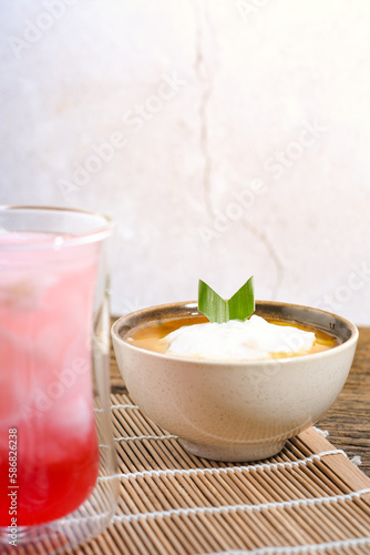 Bubur Sumsum served on wooden table, Javanese dessert porridge of rice flour, coconut milk with brown sugar syrup. A popular iftar food for breaking the fast Ramadan