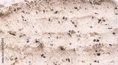 Close-up of Cookies and Cream flavored ice cream being scooped into grooves by a steel spoon.