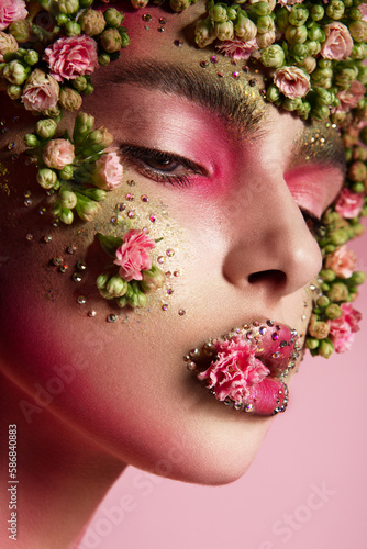 Beautiful romantic young woman with flowers on her face. Inspiration of spring and summer. Perfume, cosmetics concept.