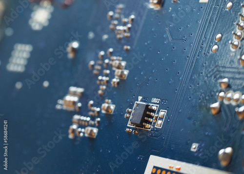 Surface-mount componenets, microchip, connection lines on the electronic circuit. High tech background with blue circuit board texture. 	 photo