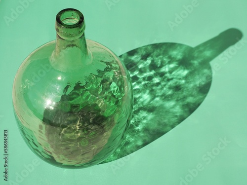 Fotografie botella verde de cristal verde damajuana y su sombra