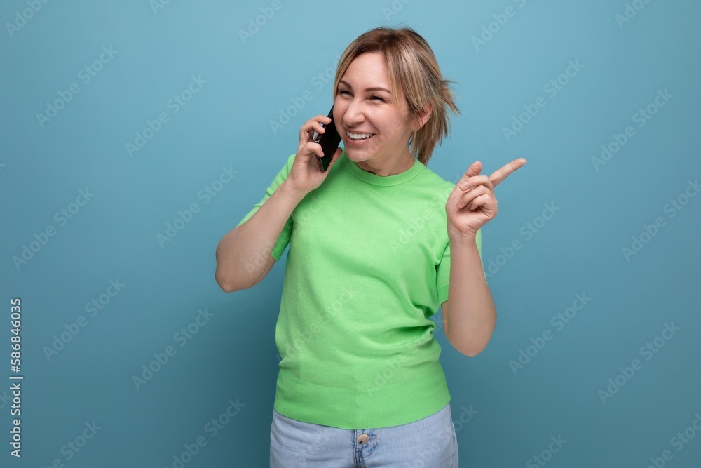 horizontal photo of a cheerful joyful adorable blond woman with a smartphone in her hands on a blue background with copy space horizontal photo of a cheerful joyful adorable blond woman with a smartphone in her hands on a blue background with copy space